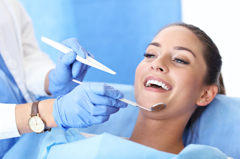 a woman smiles as she receives a dental examination